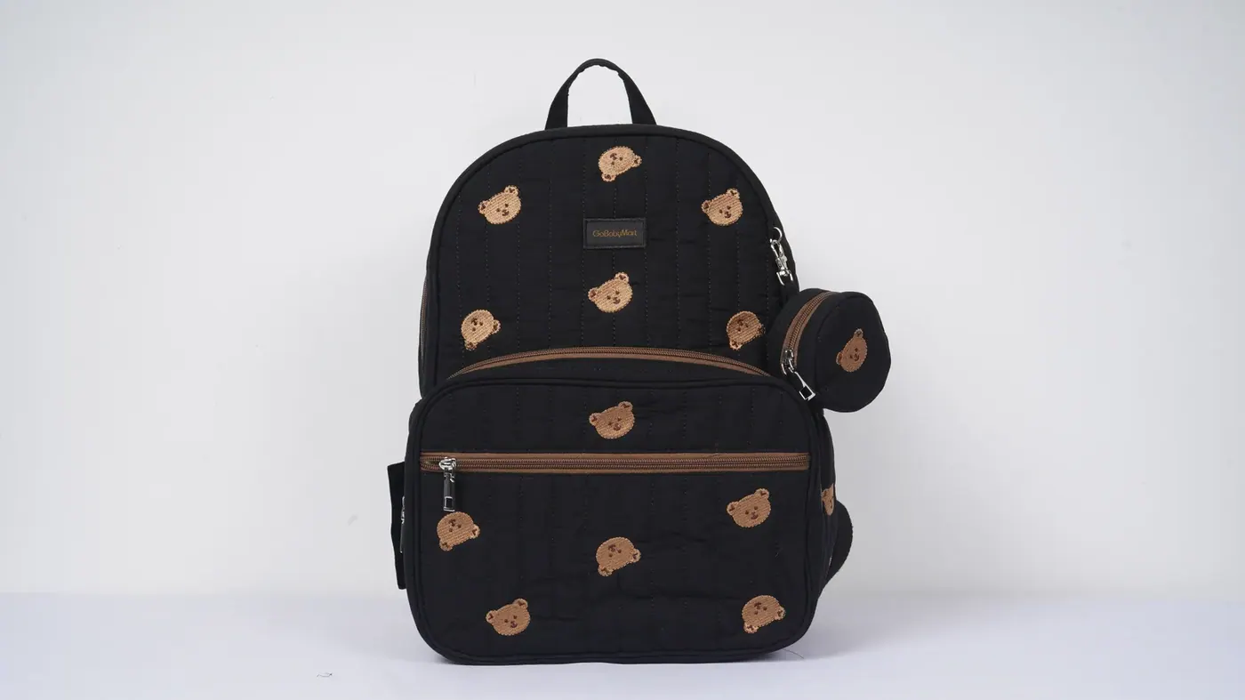 Budget waterproof backpack opened on a workbench showing the roll-top closure, welded seam and coated base panel