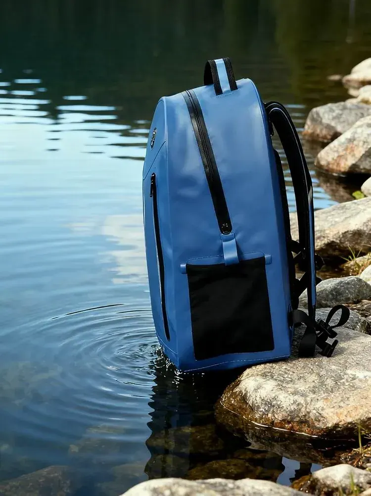 Waterproof outdoor daypack in the 25 litre class carried on a mountain trail with side compression straps tightened and a water bottle in an external pocket