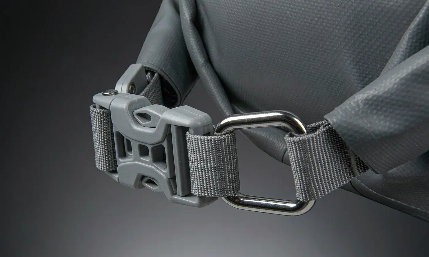 Close-up of a side release buckle and a stitched D-ring attachment on a waterproof backpack webbing strap