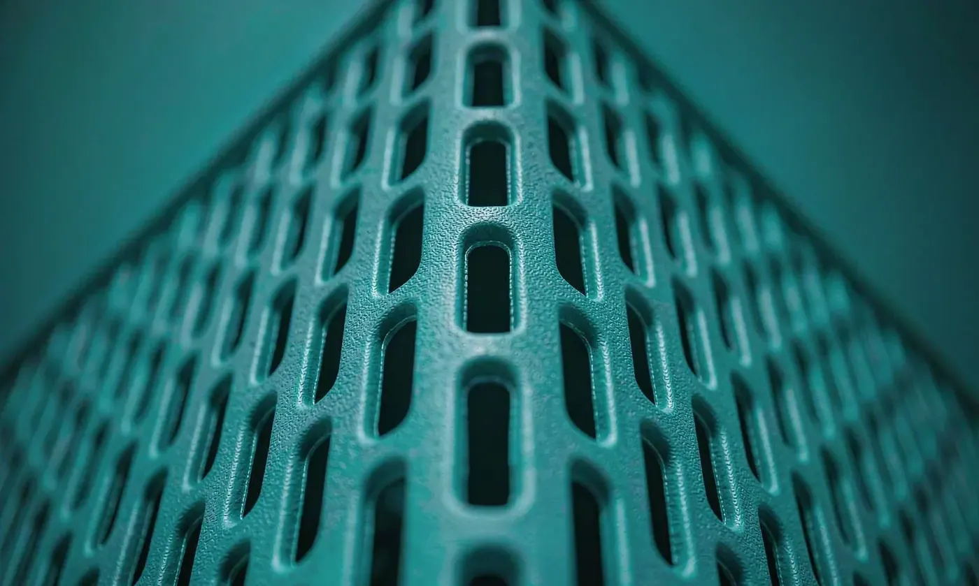 Macro photograph of perforations in an EVA tote wall showing clean molded hole edges and the solid band above