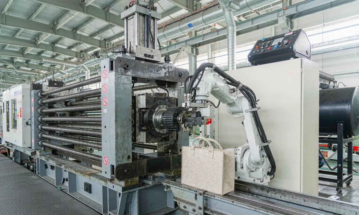 Industrial moulding press with a heated platen closing on an EVA sheet during the forming stage of tote production