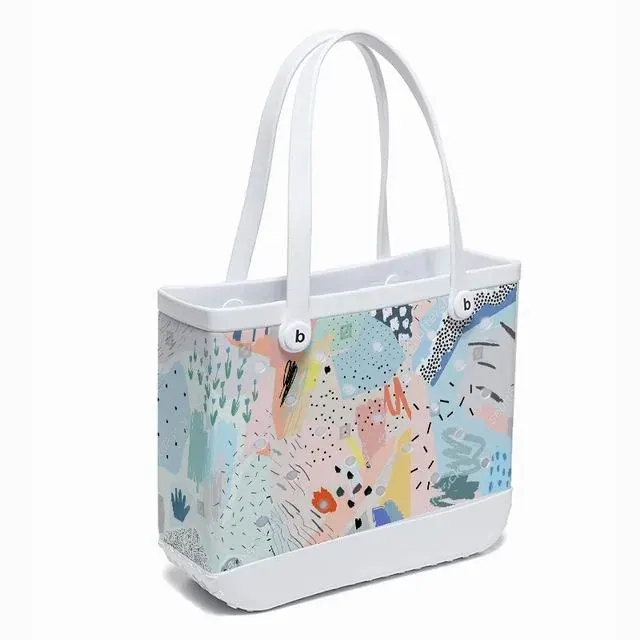 Small perforated EVA tote in a bright colour standing on a poolside bench beside goggles and sunscreen