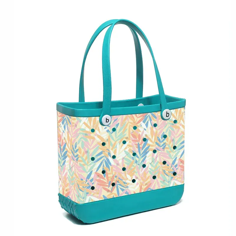 Perforated EVA tote lifted out of shallow water with water streaming through the holes while drying on sand