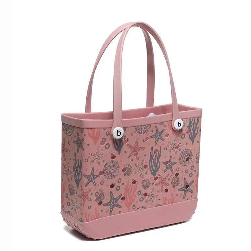 Perforated EVA tote standing upright on uneven sand while a soft canvas tote beside it has folded over