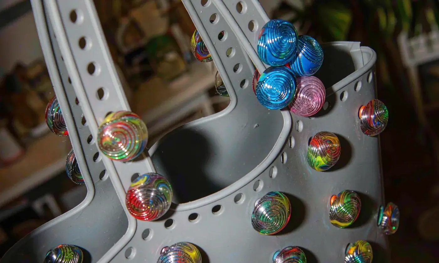 Close view of pressed silicone charms seated in the perforations of an EVA tote wall in mixed colours