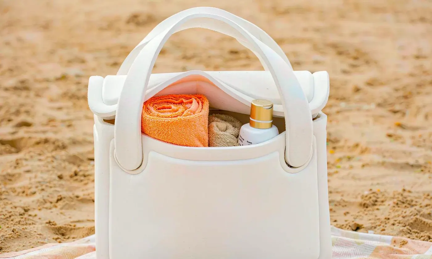 Perforated EVA tote packed with a rolled towel, a bottle and small items standing on a shaded patio after a grooming session