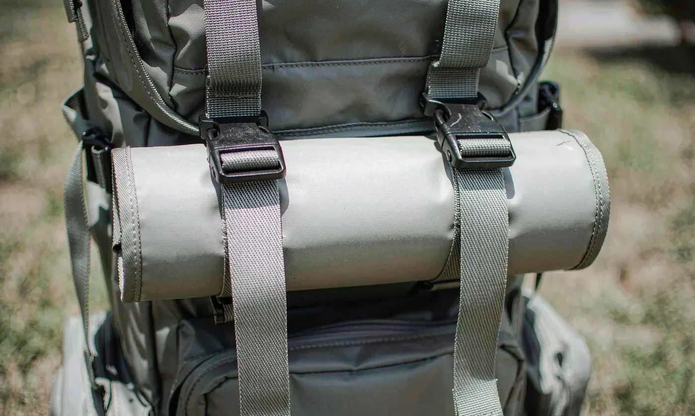 Close-up of the moulded rod holder attachment point on a large fishing tackle backpack showing the webbing and bar-tack stitching