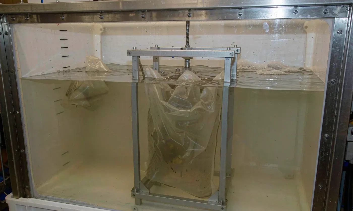 Waterproof backpack material sample and sealed body undergoing a timed immersion test in a clear IPX8 water tank