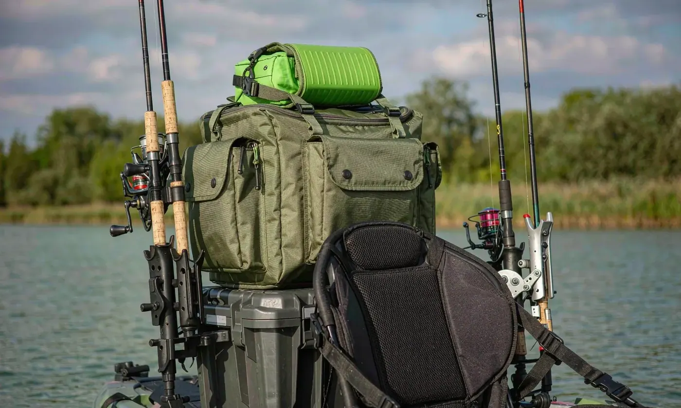 Close view of a rigged kayak crate with a waterproof dry backpack strapped in, showing a woven shell face and reinforced webbing attachment points