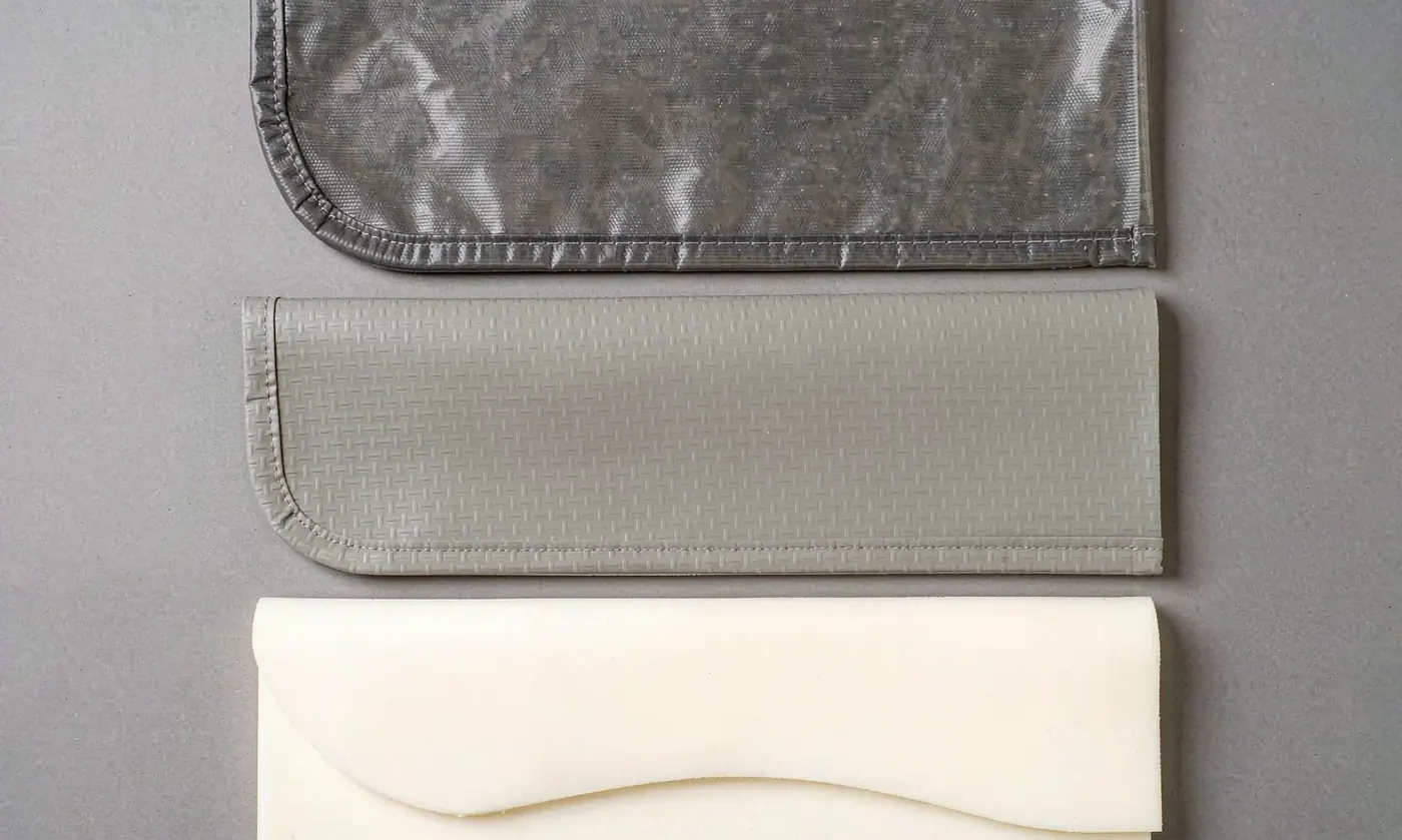 Flat-lay comparison of waterproof shell fabric swatches showing a TPU laminate, a coated ripstop and welded seam samples placed side by side on a neutral surface