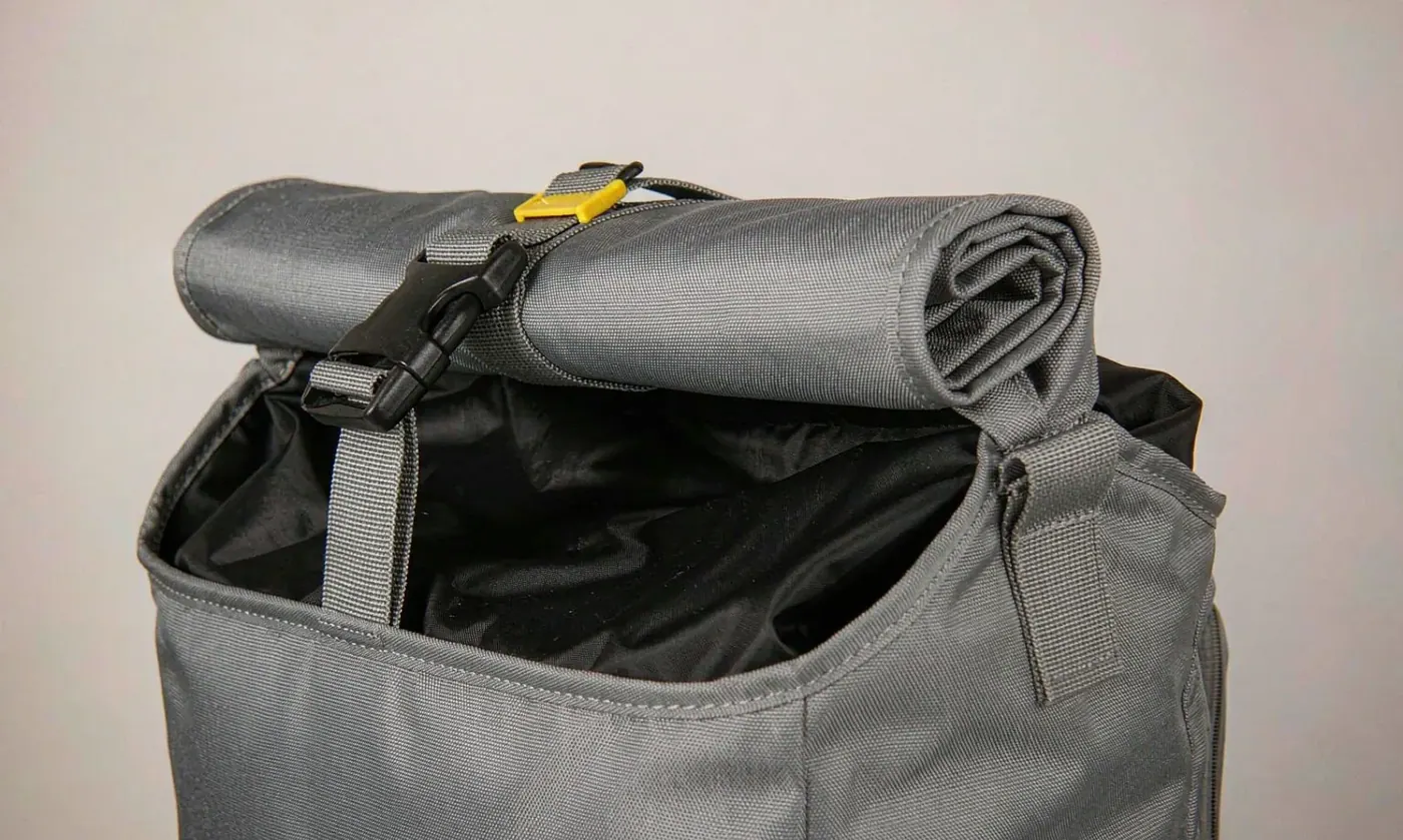 Studio close-up of a roll top closure on a waterproof backpack showing the coated fabric face, the welded seam and the stiffener strip