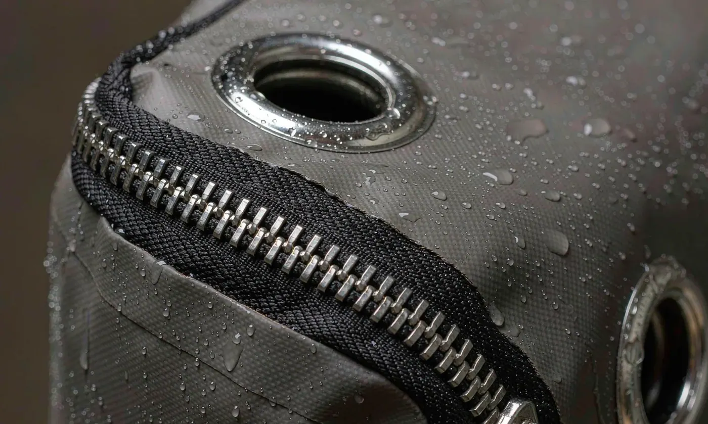 Close-up of corrosion resistant hardware and a reinforced stitched joint at a waterproof backpack strap anchor point